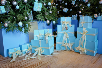 Green New Year tree. Decorated Christmas room with beautiful fir tree .Christmas and New Year's Day , blue gifts . Collection of little handmade gift boxes in a snow covered miniature evergreen forest