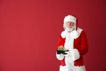 Fototapeta na wymiar Santa Claus with money on color background