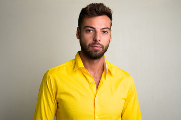 Obraz premium Studio shot of young handsome bearded businessman wearing yellow shirt
