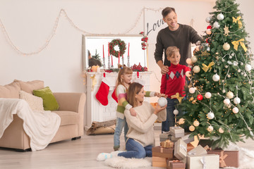 Happy family decorating Christmas tree in room