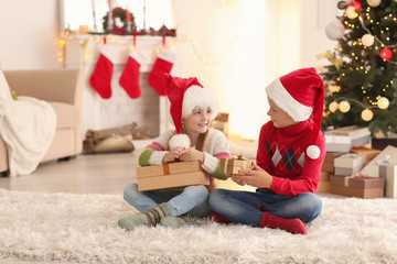Obraz na płótnie Canvas Cute children with Christmas gifts at home