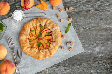 Parchment with delicious peach galette on table