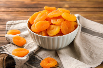 Bowl with dried apricots on table