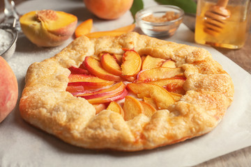 Parchment with delicious peach galette on table