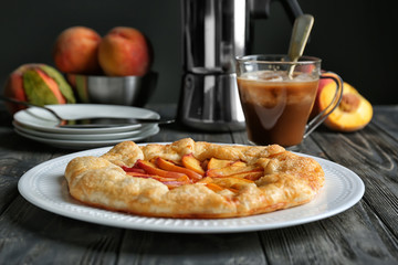 Plate with delicious peach galette on wooden table