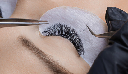 Eyelash extension procedure. Woman master making long lash - obrazy, fototapety, plakaty