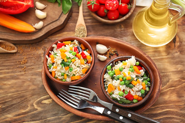 Tasty boiled rice with vegetables in bowls on wooden table