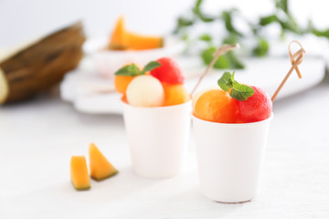 Cups with fresh melon and watermelon balls on light table