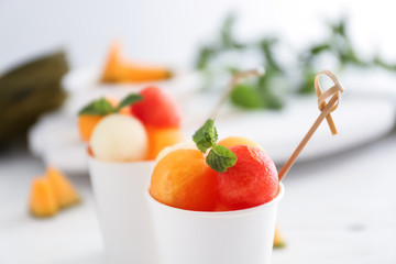 Cup with fresh melon and watermelon balls on table, closeup