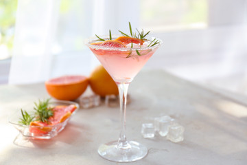 Fresh grapefruit cocktail with rosemary in glass on light table