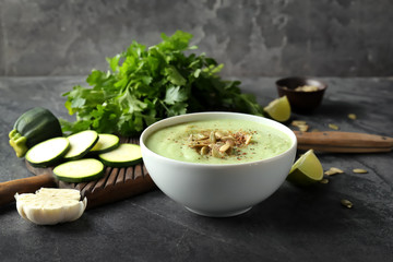 Tasty zucchini soup with pumpkin seeds in bowl on dark table