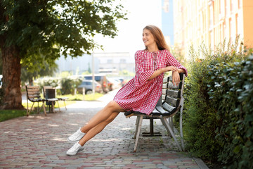 Beautiful young woman resting on wooden bench in park