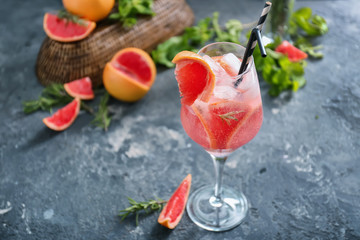 Fresh grapefruit cocktail with rosemary in glass on grey table