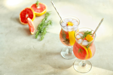 Fresh grapefruit cocktail with rosemary in glasses on light table