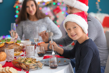 Cute boy and his family having Christmas dinner at home
