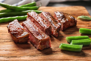 Cut grilled steak with green beans on wooden board