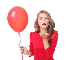 Beautiful young woman with balloon blowing kiss on white background