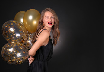 Beautiful young woman with balloons on dark background