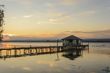 Fototapeta premium wooden Fishing hut in a lake with pier and fishing net at sunset.