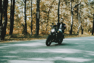Motorcycle Biker Rides On Highway In A Forest.