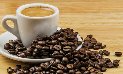 Espresso in coffee cup with coffee beans on wooden desk