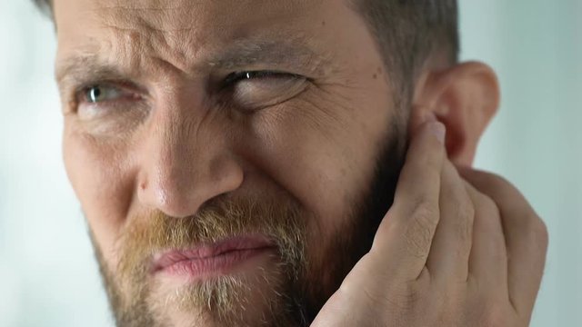 Man disturbed by painful stuffiness in ear infection or inflammation, healthcare