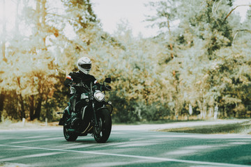 Fototapeta na wymiar Biker In Helmet Is Riding On Highway In A Forest.