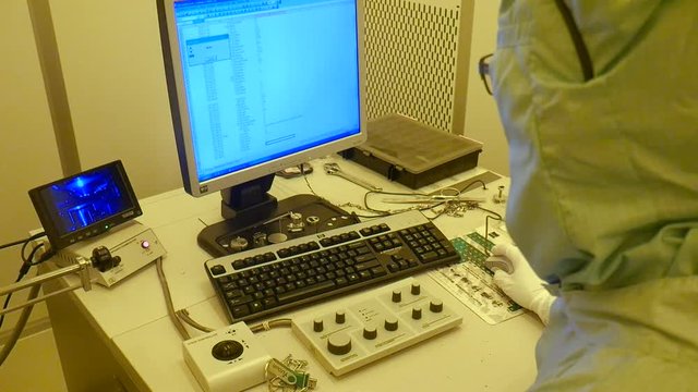 A shot of the back of a scientist working on a big electrone microscope.