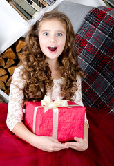 Adorable surprised little girl in princess dress holding gift box