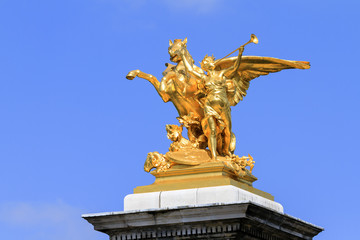 Fototapeta premium Golden statue against a blue sky on top of the pont Alexandre III at Invalides in Paris, France 