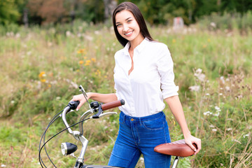 Obraz premium Pretty girl with a bicycle posing outdoors
