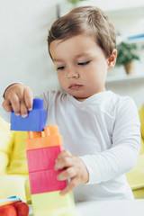 toddler playing with colorful constructor blocks at home