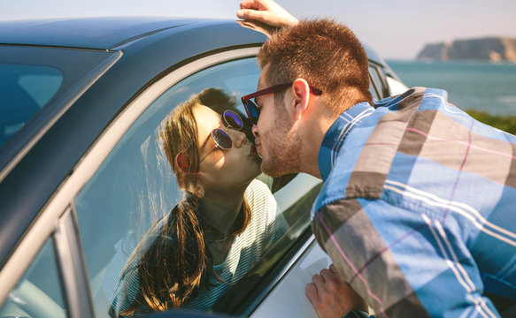 Young couple kissing through the glass of the car outdoors