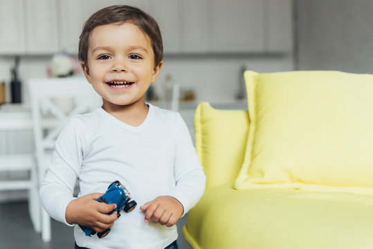 Adorable Smiling Boy Holding Toy Car At Home