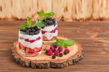 Trifle close up photography with fresh multi layered dessert with dairy and ripe raspberries and blackberries.