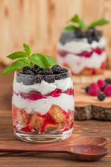 Trifle close up photography with fresh multi layered dessert with dairy and ripe raspberries and blackberries.