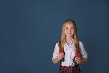 Cute schoolgirl with backpack on color background
