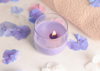 Burning candle with hydrangea flowers on light table