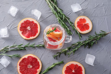 Fresh grapefruit cocktail with rosemary in mason jar on grey table
