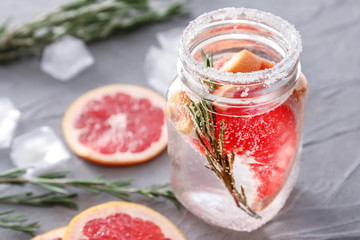 Fresh grapefruit cocktail with rosemary in mason jar on grey table