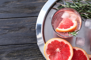 Fresh grapefruit cocktail with rosemary in glass on metal tray