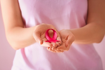 Woman holding pink ribbon, closeup. Breast cancer concept