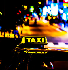 Taxi in the city at the dark. Car with glowing taxi sign moving in the night