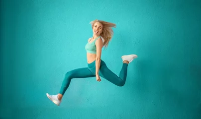 Gordijnen Sporty woman jumping near color wall © Pixel-Shot