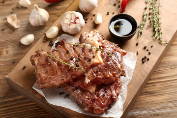 Delicious grilled steaks with spices on wooden board