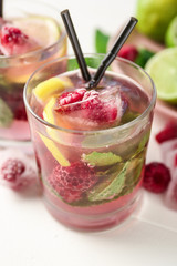 Glass of fresh raspberry mojito on light table