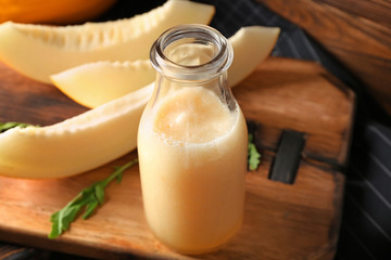 Bottle of fresh melon smoothie on wooden board