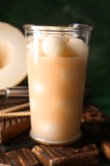 Glass of fresh melon smoothie on wooden board
