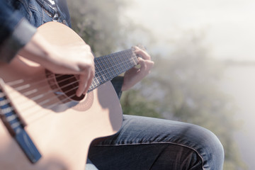 Fototapeta premium Female hands close up playing guitar on background in blur