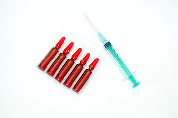 Syringe and ampoules with medicine of red color on a white background